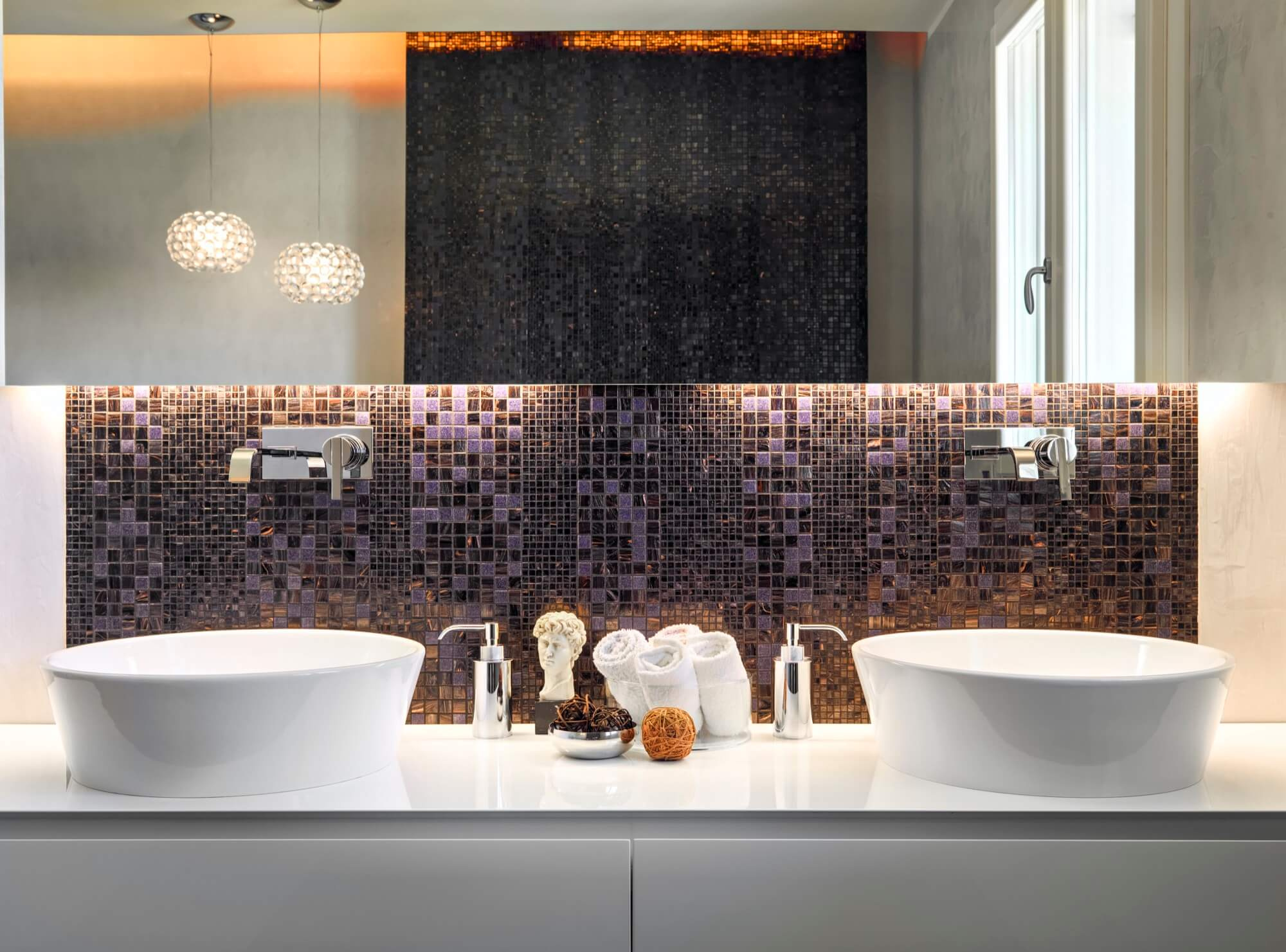 Stilrent badrum med dubbla ovanpåliggande handfat, väggmonterade blandare och mosaikkakel – badrumsrenovering i modern stil.
